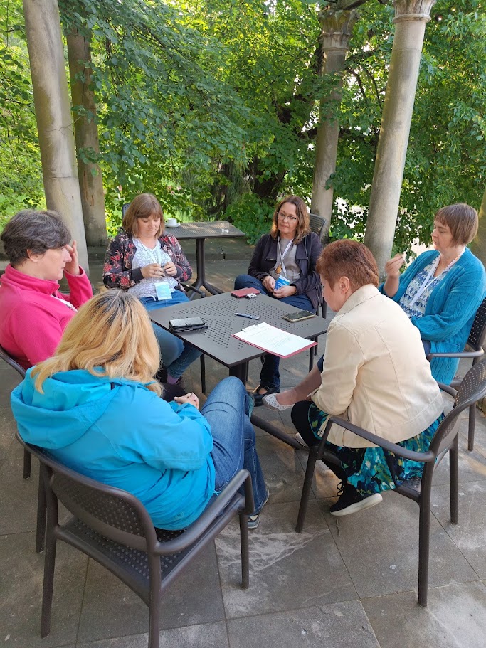 Na zdjęciu widać stół, przy którym siedzą osoby wspólnie dyskutujące